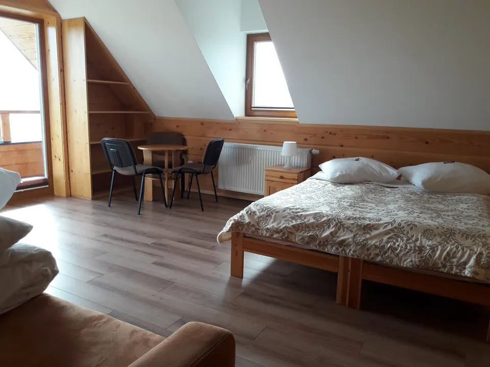 Jasny pokój z łóżkiem i biurkiem pod skosem dachu