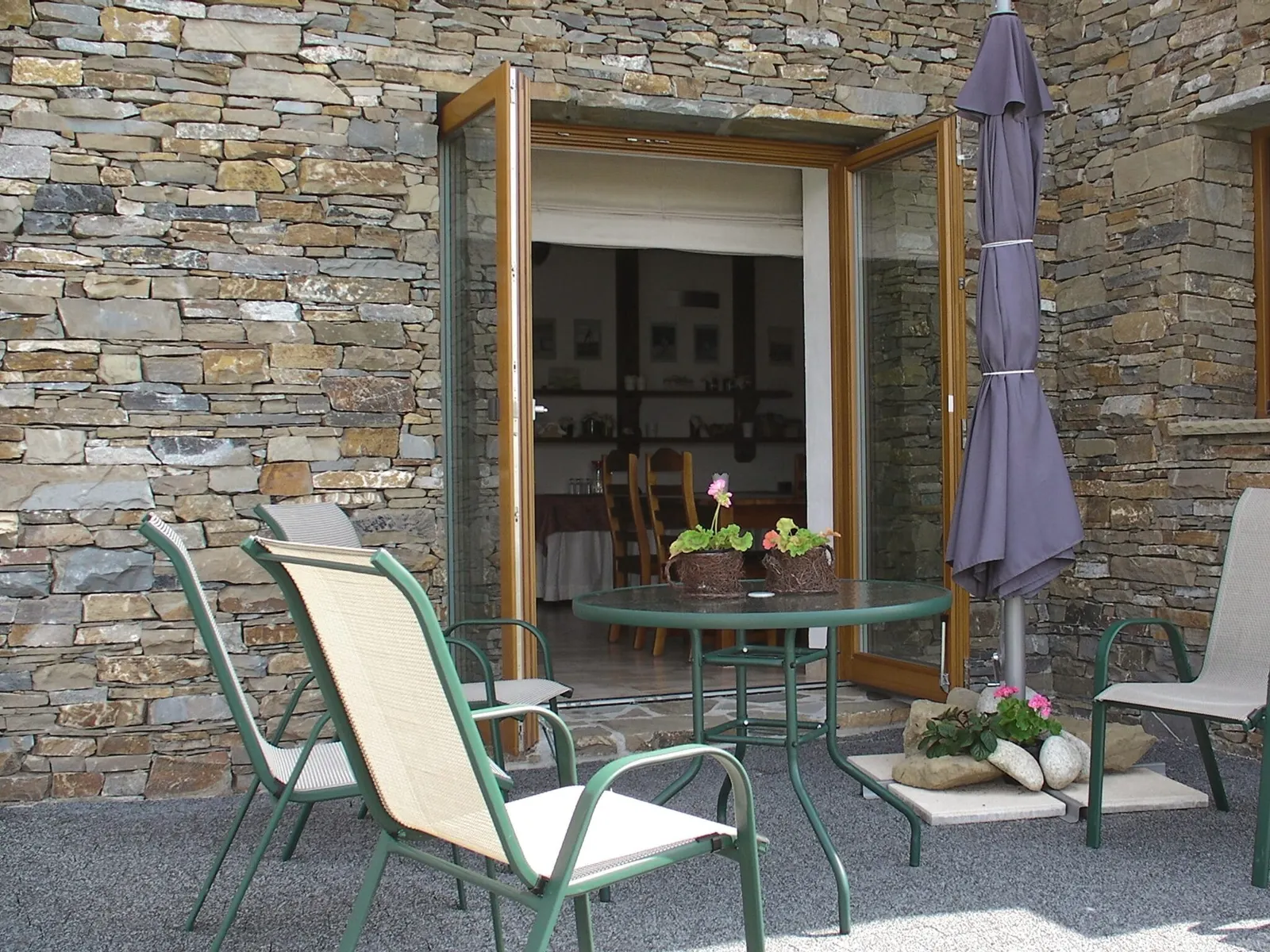 Patio z kamienną ścianą, stolikiem i krzesłami na zewnątrz